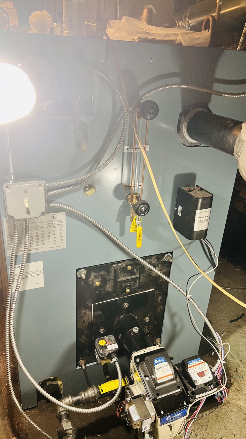 Oil-fired residential boiler with burner, controls, and hydronic piping during field service